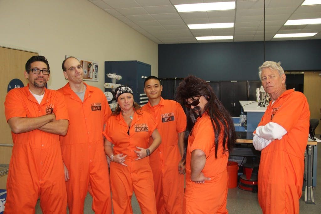 engineering team members dressed up for Halloween in orange jump suits like prison inmates